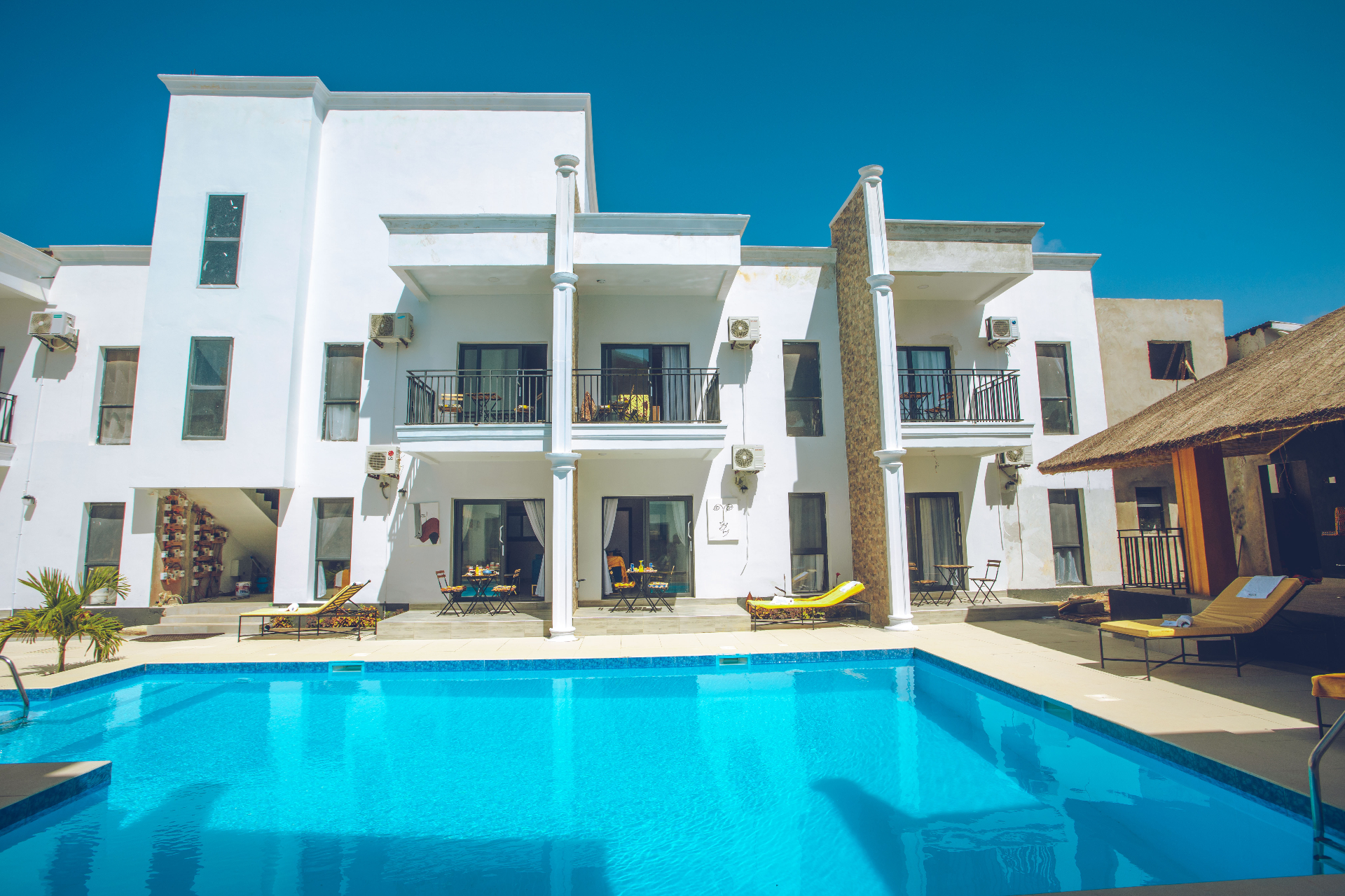 MICA Apartments pool with full villa facade and thatched bar